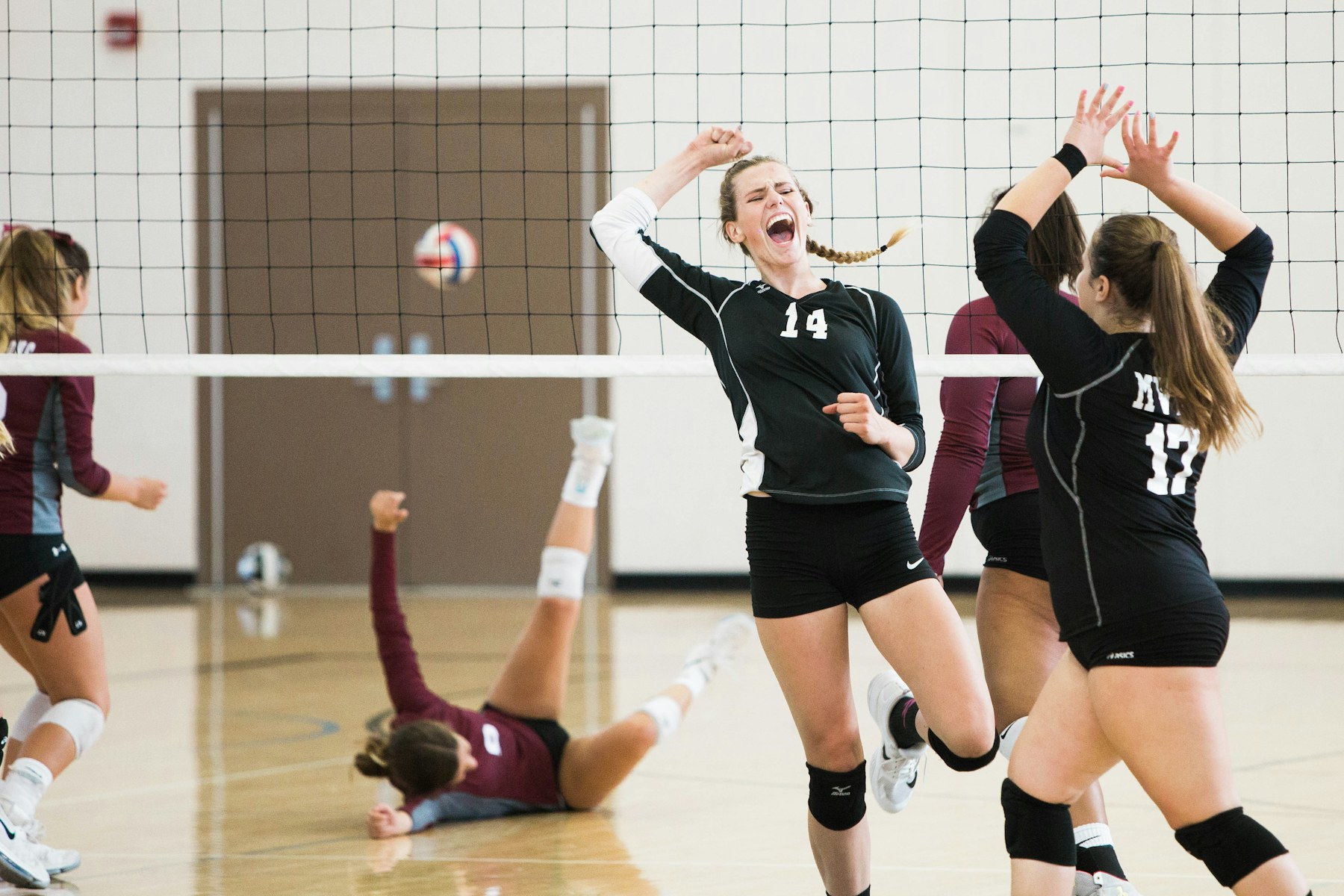 Volleyball players celebrating together on an indoor court